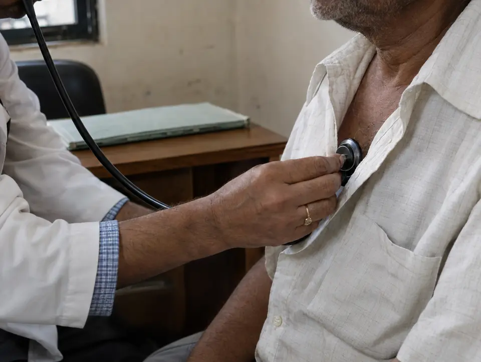 A surgeon listening to an older man's chest with a stethoscope during a post-operative check