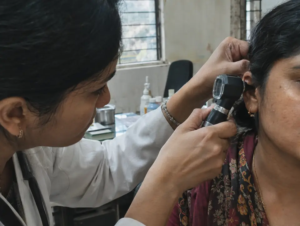 An otoscope held at a patient's ear by a doctor's hand