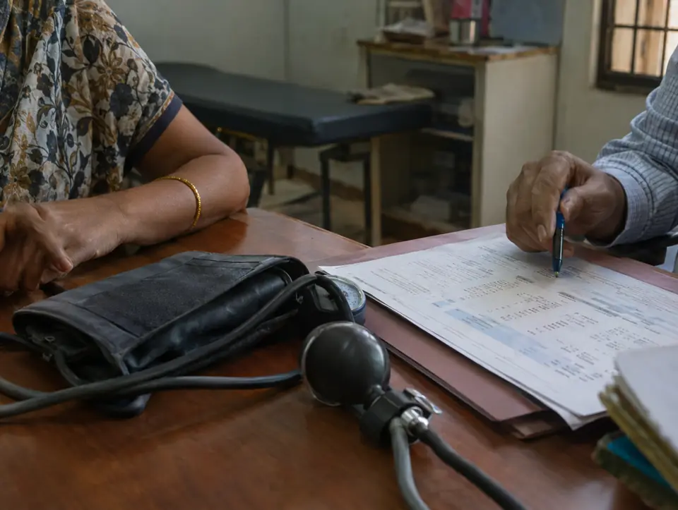 A blood pressure monitor cuff and a printed lab report on a desk